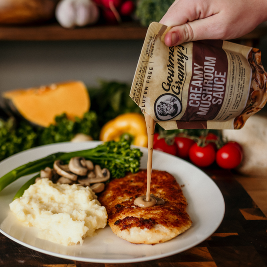 Hand pouring Creamy Mushroom Sauce over a plate of food with vegetables in the background