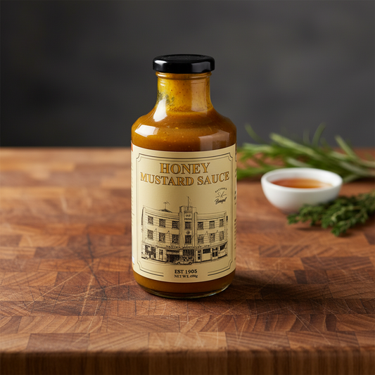 Bottle of honey mustard sauce on a Wooden cutting board with other garnish in the background