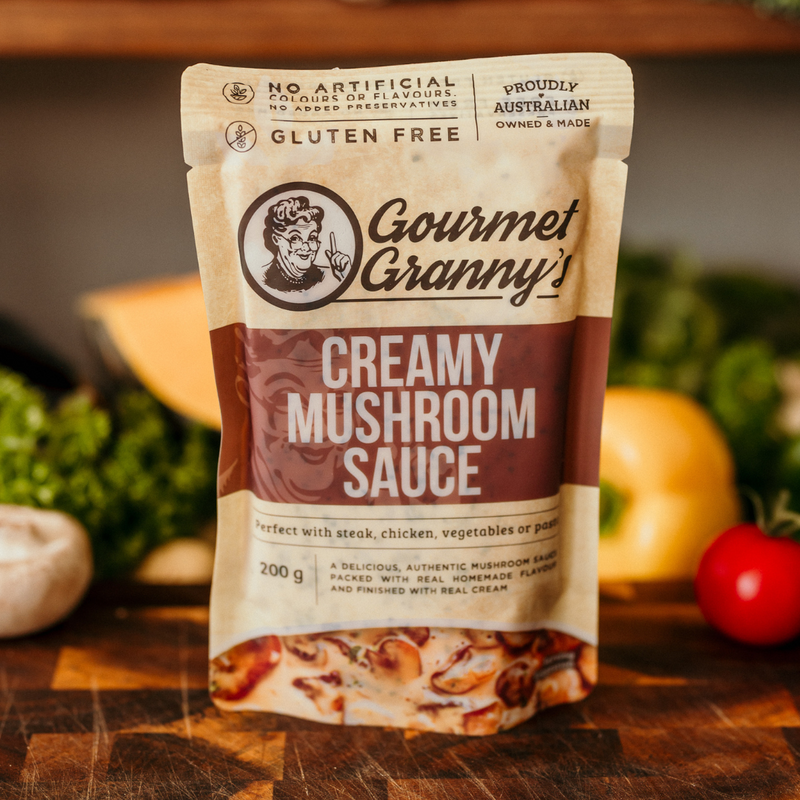 Gourmet Granny creamy mushroom sauce packet on a wooden surface with vegetables in the background