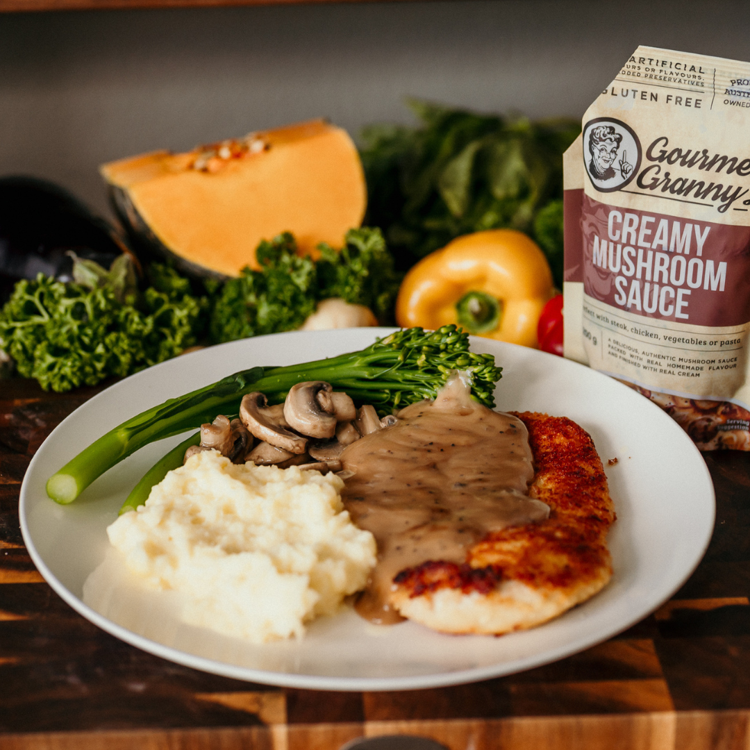 Plate of food with creamy mushroom sauce, surrounded by vegetables and a pouch of Gourmet Granny sauce.