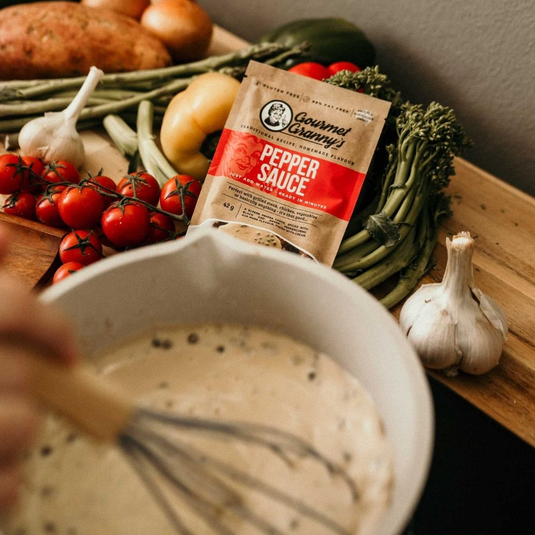 Gourmet Granny pepper sauce packet on a wooden board with vegetables and a bowl of creamy mixture.