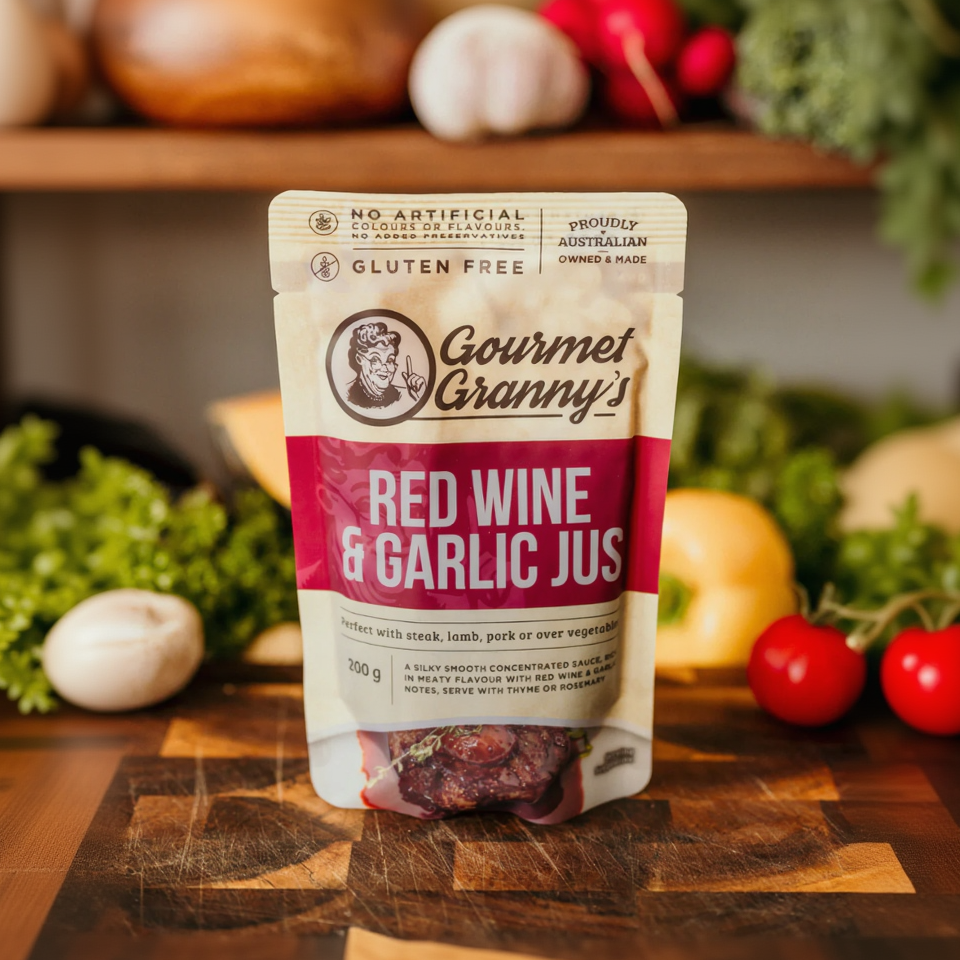 Gourmet Granny's Red Wine & Garlic Jus package on a wooden surface with vegetables in the background