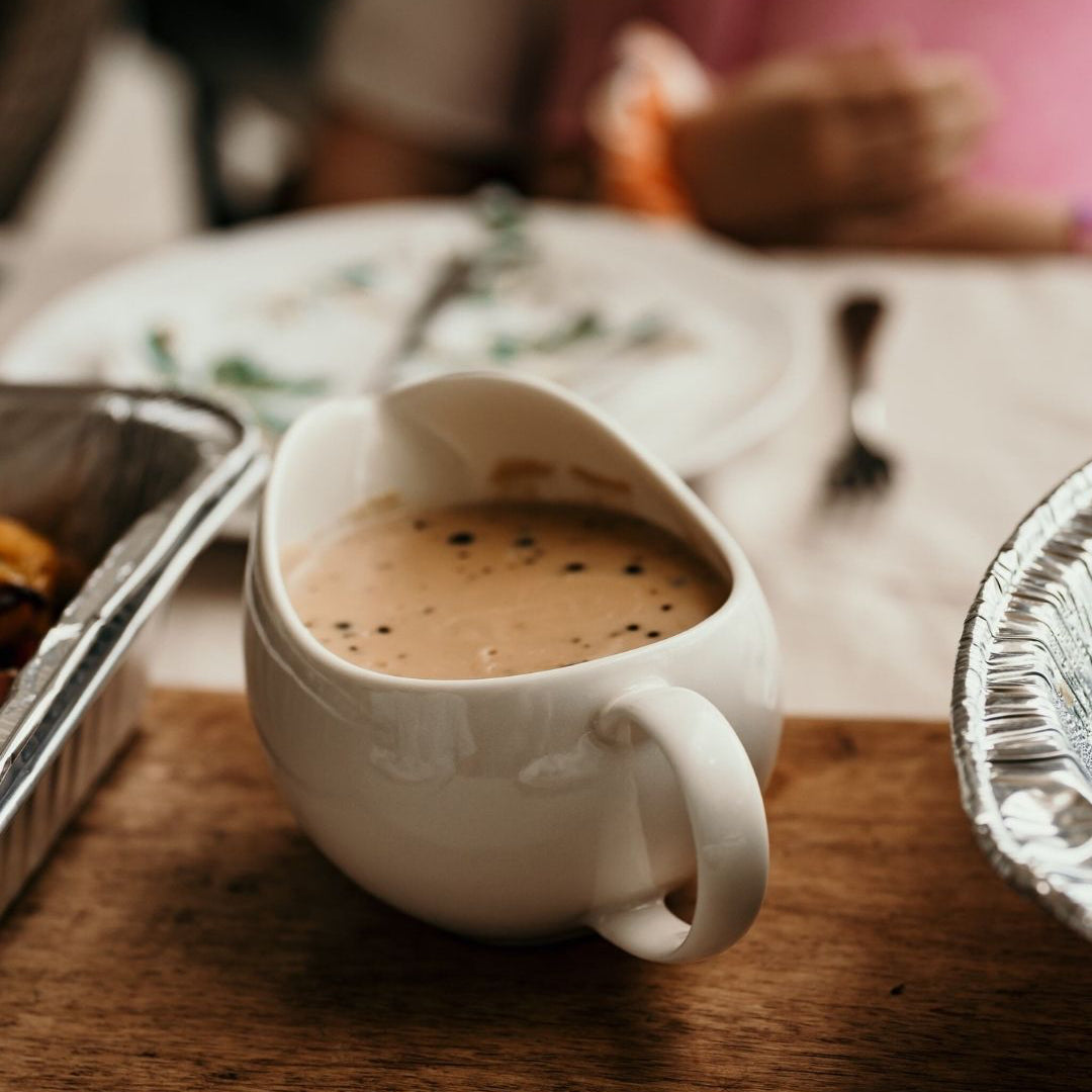 White Gravy Boat filled with Diane Sauce on a wooden surface